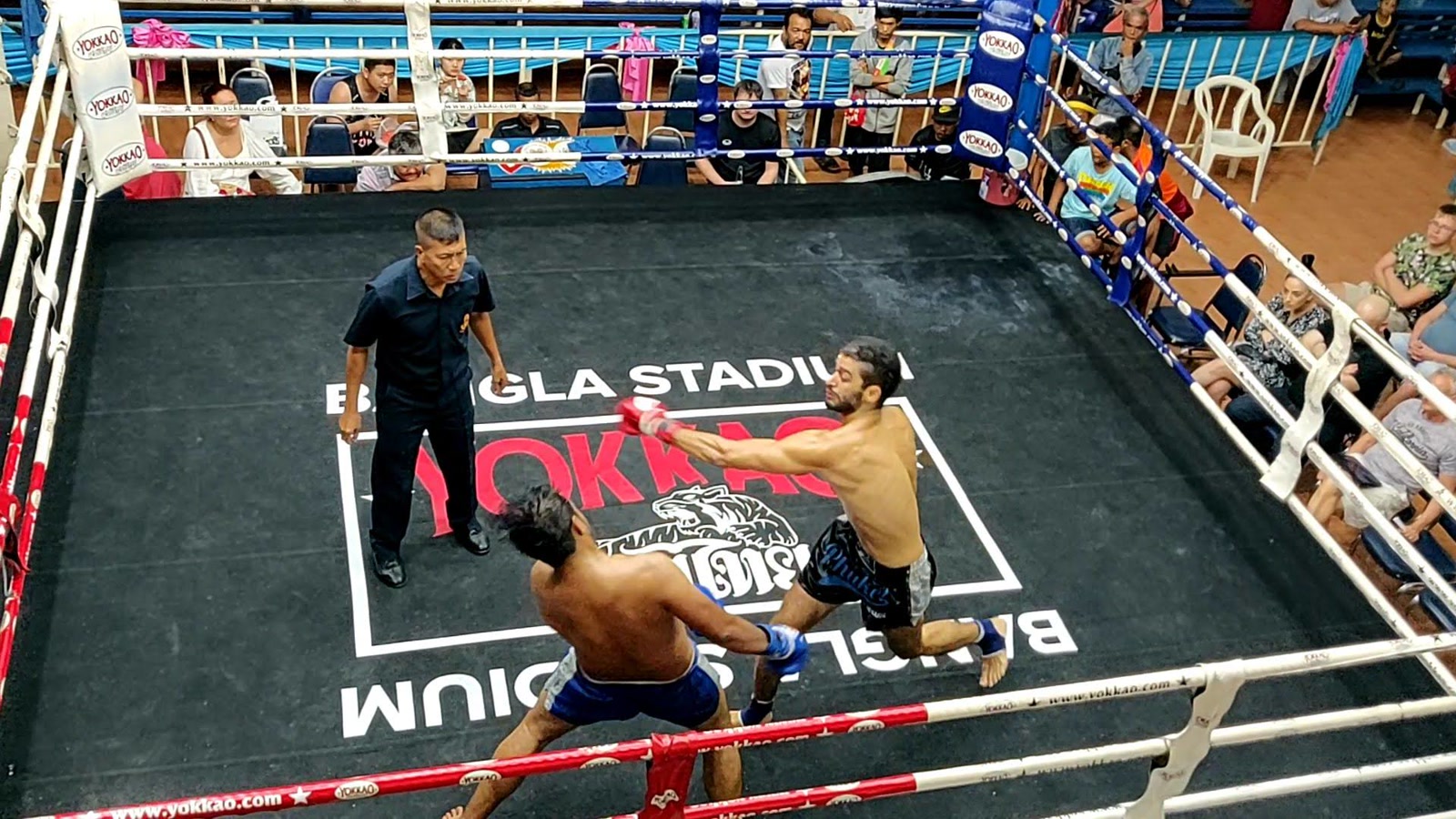 Taieb, in red gloves, throwing a punch toward his opponent during a Muay Thai fight in Thailand.